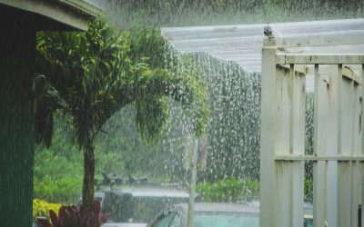 Overflowing gutter in heavy Hawaii rain, water pouring off roof edge and risking leaks and water damage
