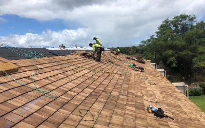 ProBuilt Hawaii crew installing cedar shake roof with safety harnesses on a large home.