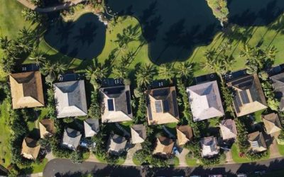 Aerial view of Hawaii homes with different roofing materials surrounded by palm trees and green landscaping.
