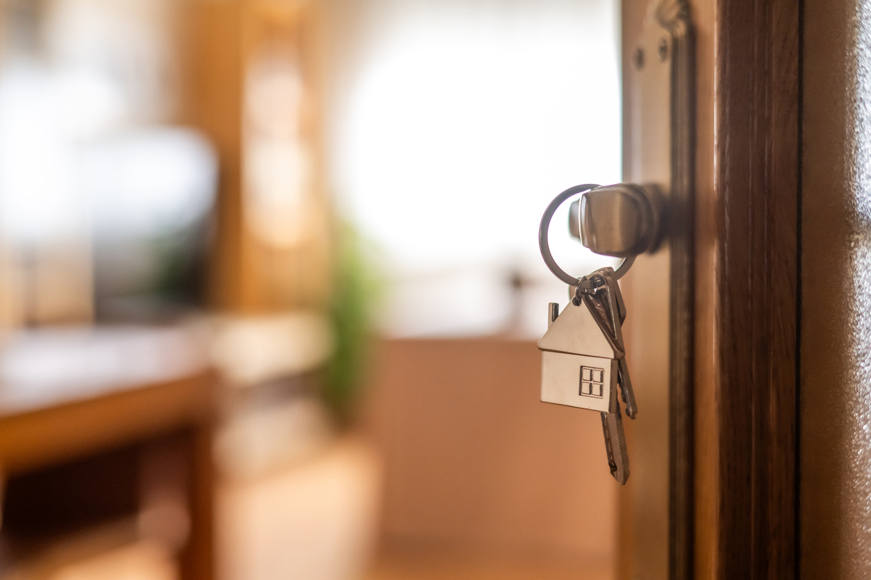 House keys with a home-shaped keychain in the door of a Hawaii house being sold