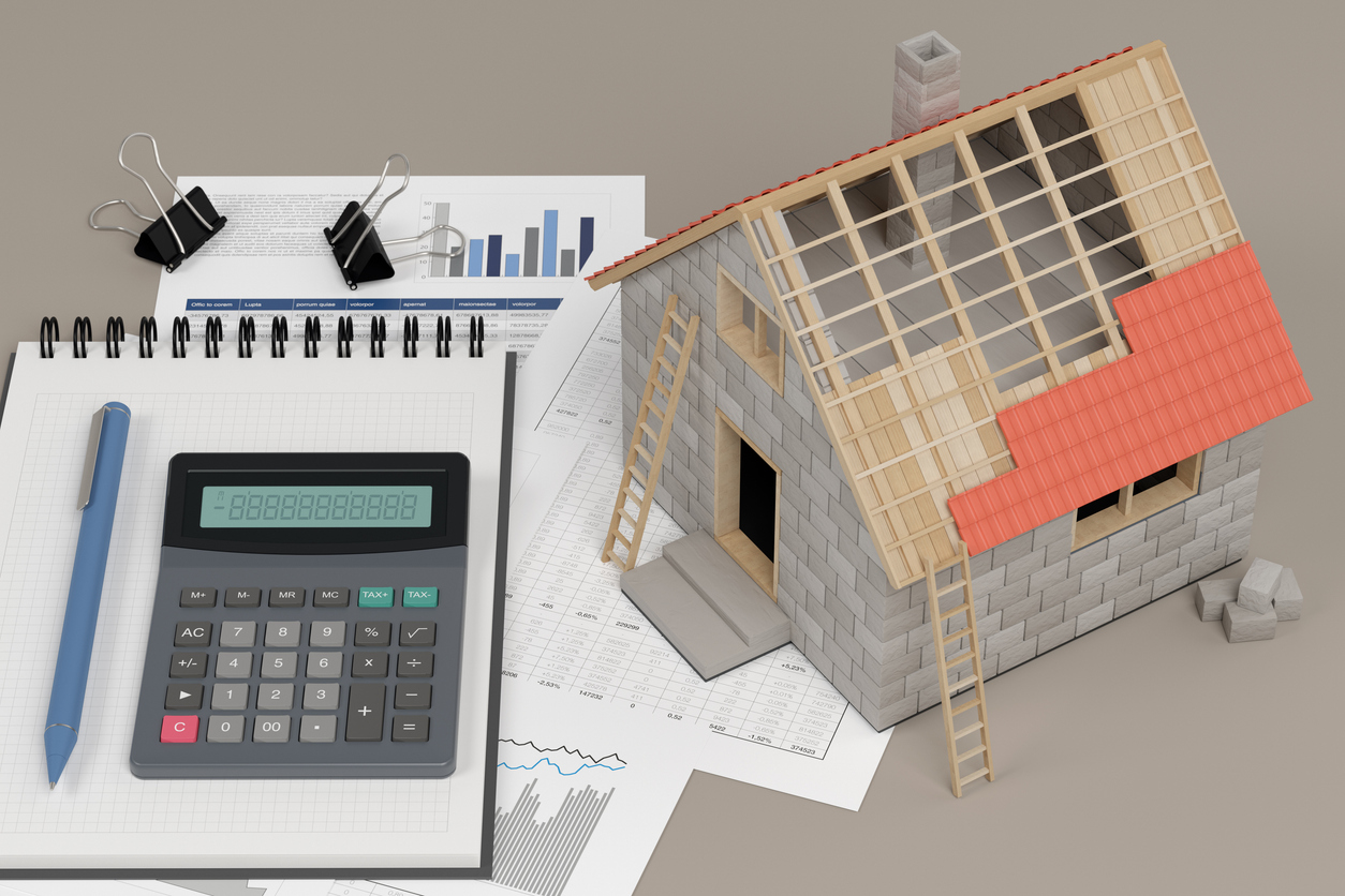 Calculator and itemized cost sheets for comparing roof replacement quotes, next to a model house with a partly tiled roof